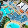 Vista dall'alto di un parco acquatico con ombrelloni blu e piscine.